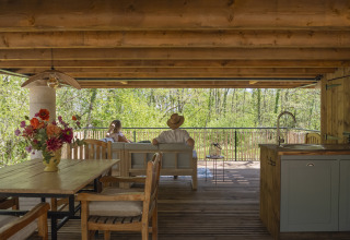Mensen ontspannen in de boomhut Duiventoren op Camping Les 3 Cantons in Frankrijk, met boszicht.