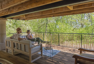 Twee mensen ontspannen op het terras van de Duiventoren-boomhut op Camping Les 3 Cantons, Frankrijk.