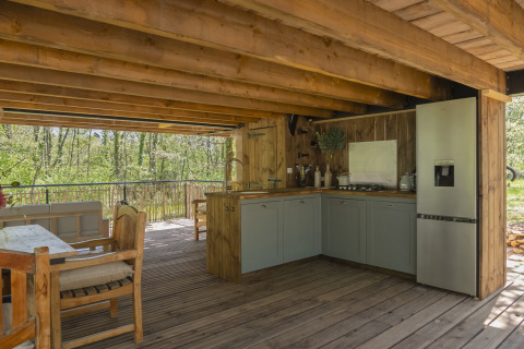 Boomhutkeuken bij Duiventoren, Les 3 Cantons, Frankrijk, met houten meubels en uitzicht op het bos.