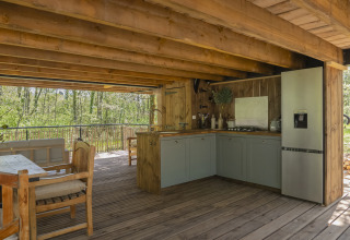 Boomhutkeuken bij Duiventoren, Les 3 Cantons, Frankrijk, met houten meubels en uitzicht op het bos.
