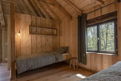 Boomhut Duiventoren bij Camping Les 3 Cantons in Frankrijk met eenpersoonsbed, houten muren en raam.