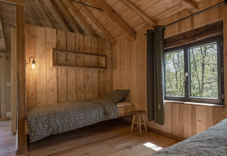 Boomhut Duiventoren bij Camping Les 3 Cantons in Frankrijk met eenpersoonsbed, houten muren en raam.