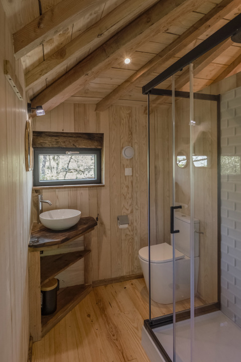 Badkamer in de boomhut Duiventoren op camping Les 3 Cantons in Frankrijk, modern en houten interieur.