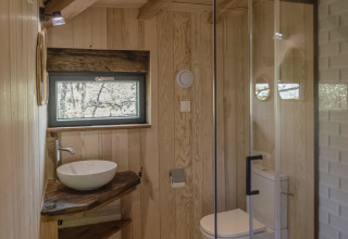 Badkamer in de boomhut Duiventoren op camping Les 3 Cantons in Frankrijk, modern en houten interieur.