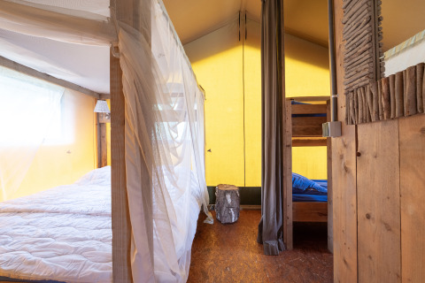 Intérieur d'une tente safari Woodlodge avec lit double, lits superposés et décoration en bois rustique.