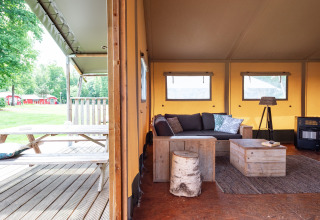 Safari tent Woodlodge interior with rustic wooden furniture, cozy lounge area and outdoor picnic table view.