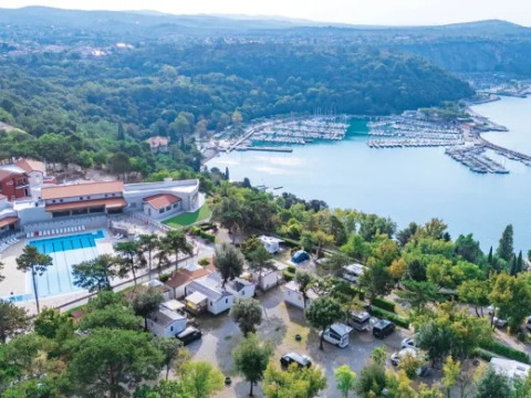 Vista aerea del campeggio Village Mare Pineta in Italia con piscina, case mobili, alberi e porto turistico.