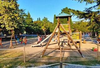 Children playing on a playground with slides and wooden structures at Village Mare Pineta campsite, Italy.