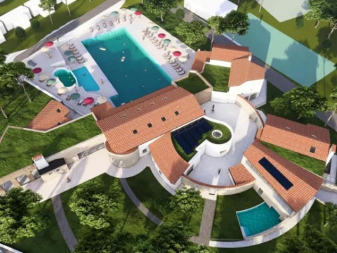 Vista aerea di Village Mare Pineta con piscine, ombrelloni e edifici con tetto rosso in Friuli-Venezia Giulia.