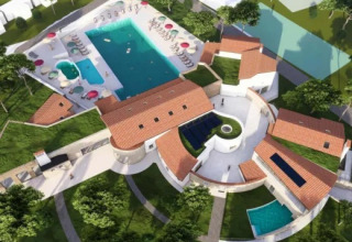 Aerial view of Village Mare Pineta campsite in Italy showing pools, patios, and red-roofed holiday buildings.