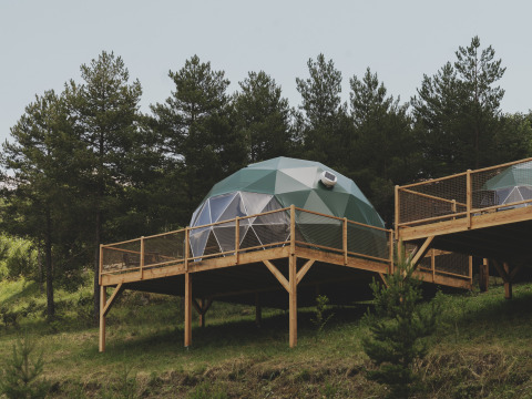 Geodetische koepel ‘Domo’ Family op houten terras bij Wecamp Pedraforca, Spanje, omgeven door bomen.