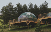 Geodetische koepel ‘Domo’ Family op houten terras bij Wecamp Pedraforca, Spanje, omgeven door bomen.