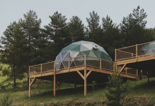 Geodetische koepel ‘Domo’ Family op houten terras bij Wecamp Pedraforca, Spanje, omgeven door bomen.
