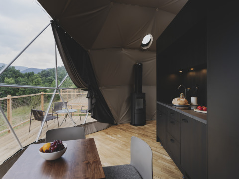 Modern koepelinterieur met keuken en eettafel, uitzicht op de natuur bij Wecamp Pedraforca in Spanje.