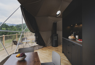 Modern koepelinterieur met keuken en eettafel, uitzicht op de natuur bij Wecamp Pedraforca in Spanje.