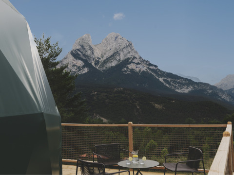 Uitzicht vanaf de Domo Family-koepel bij Wecamp Pedraforca in Spanje, met terras, bergen en stoelen.