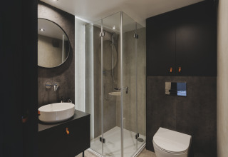Moderne badkamer bij Domo Family van Wecamp Pedraforca met glazen douche, wandtoilet en ronde spiegel.
