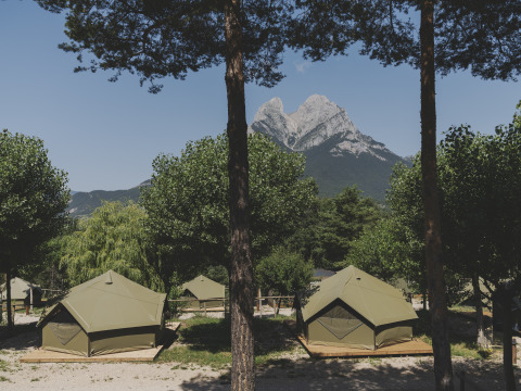Safaritenten op houten platforms op een camping, met op de achtergrond een imposante bergtop.