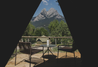 Gezicht vanuit de Bell Tent op Wecamp Pedraforca, Spanje, met een terras, stoelen en bergen op de achtergrond.