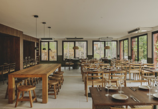 Modern restaurantinterieur in Wecamp Pedraforca, vakantiepark in Catalonië, met houten tafels en stoelen.