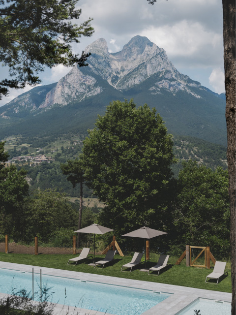 Ligstoelen en parasols bij het zwembad met uitzicht op de Pedraforca bij Wecamp Pedraforca, Catalonië, Spanje.