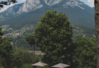 Ligstoelen en parasols bij het zwembad met uitzicht op de Pedraforca bij Wecamp Pedraforca, Catalonië, Spanje.