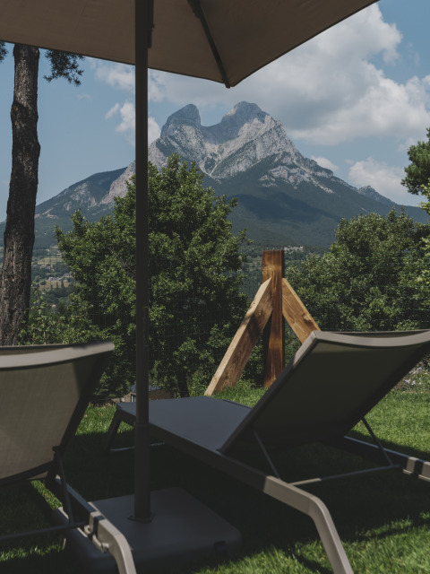 Uitzicht op de Pedraforca-berg vanuit ligstoelen onder een parasol bij Wecamp Pedraforca, Catalonië, Spanje.