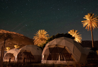 Cúpulas geodésicas y palmeras bajo un cielo estrellado en Wecamp Cabo de Gata, Andalucía, España de noche.