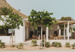 Buitenterras van Wecamp Cabo de Gata in Andalusië, Spanje, met bomen en uitzicht op bergen.