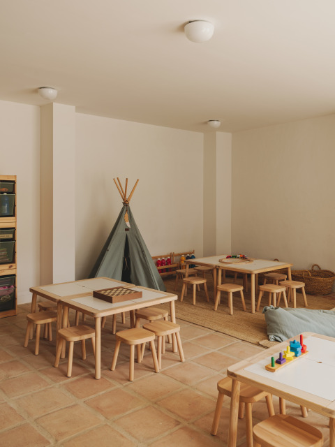 Salle de jeux pour enfants avec tables, tabourets en bois, jouets et tipi au Wecamp Cabo de Gata, Andalousie, Espagne.