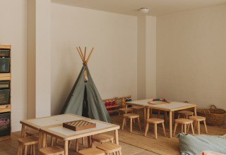 Børnevenligt legerum med træmøbler, små stole, borde, legetøj og et tipi-telt i Wecamp Cabo de Gata, Spanien.