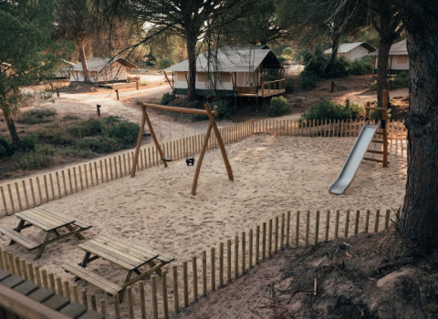 Parco giochi con altalene e scivolo circondato da bungalow presso il Wecamp Cádiz in Andalusia, Spagna.