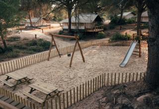 Playground with swings and a slide, surrounded by cabins at the Wecamp Cádiz holiday park in Andalusia, Spain.