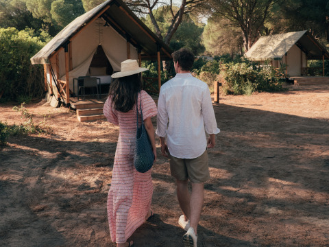 A couple walks toward a glamping tent at Wecamp Cádiz holiday park, surrounded by nature in Andalusia, Spain.