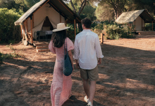 A couple walks toward a glamping tent at Wecamp Cádiz holiday park, surrounded by nature in Andalusia, Spain.