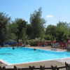 Outdoor swimming pool with people relaxing at Camping Prunay - Lodges Centre-Val de Loire on a sunny day.