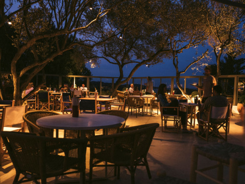 Zona de comedor al aire libre por la noche en Wecamp Cadaqués, parque vacacional en Cataluña, España, con comensales.