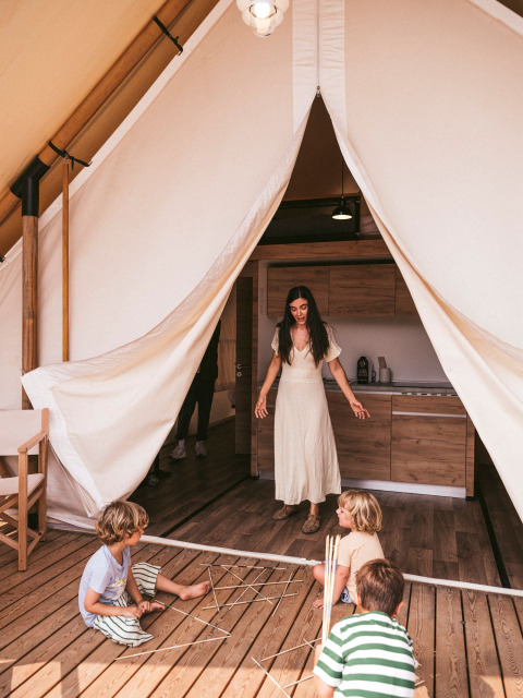 Madre e bambini giocano davanti a una tenda al Wecamp Cadaqués, villaggio turistico in Catalogna, Spagna.