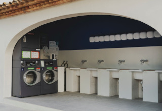 Laundry area with washing machines and sinks at Wecamp Jávea holiday park in Valencia, Spain.