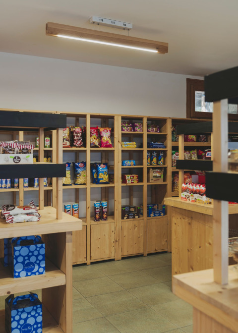Intérieur d’une petite épicerie avec des étagères en bois remplies de snacks à Wecamp Pirineos en Aragón.