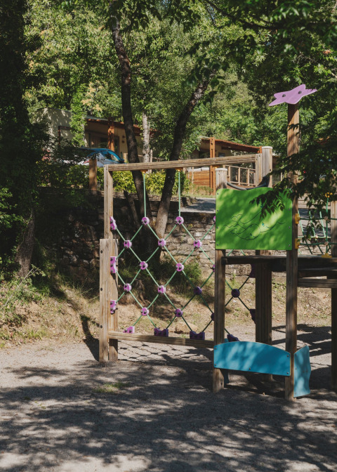 Kinderspielplatz im Wecamp Pirineos Ferienpark in Aragón, Spanien, umgeben von grüner Natur und Bäumen.