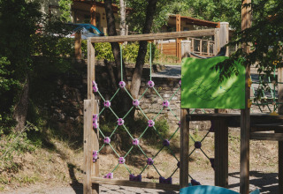 Aire de jeux pour enfants au parc de vacances Wecamp Pirineos en Aragón, Espagne, entourée d’arbres verdoyants.