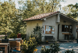 Outdoor view of a building with a noticeboard and benches at Campsite Lucherino in Tuscany, Italy.
