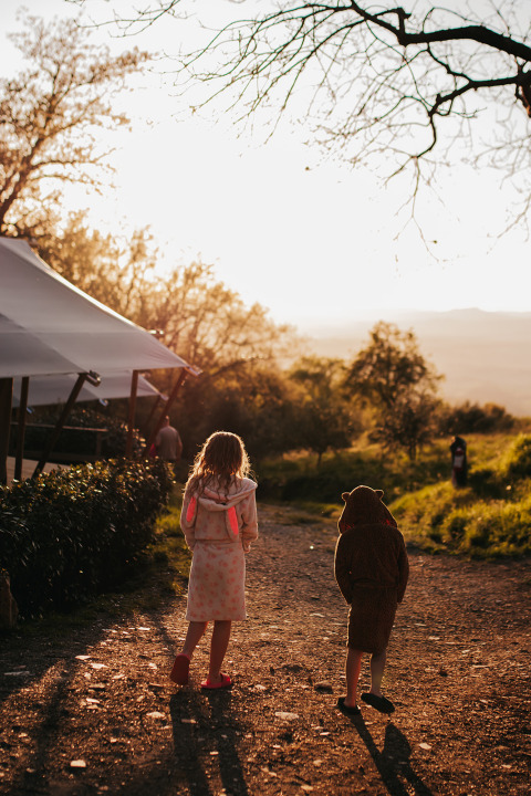 Deux enfants en peignoir marchent au coucher du soleil au camping Lucherino, en Toscane, Italie.
