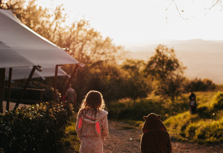Deux enfants en peignoir marchent au coucher du soleil au camping Lucherino, en Toscane, Italie.