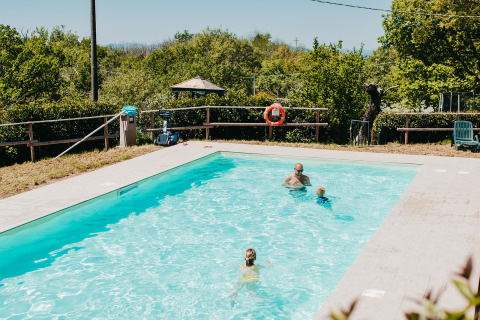 Famille profitant d'une journée ensoleillée à la piscine du camping Lucherino en Toscane, Italie.