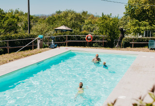 Family enjoying a sunny day in the pool at Campsite Lucherino, a scenic holiday park in Tuscany, Italy.