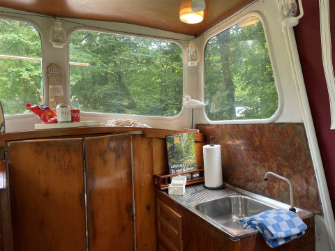 Intérieur du Cabin Boat au Buytenplaets Suydersee, Pays-Bas, avec évier, armoires en bois et fenêtres.