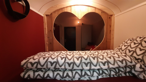 Innenraum des Pipo Love Tiny House bei Buytenplaets Suydersee, Niederlande, mit Herzfenster und Herz-Bettwäsche.