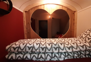 Innenraum des Pipo Love Tiny House bei Buytenplaets Suydersee, Niederlande, mit Herzfenster und Herz-Bettwäsche.
